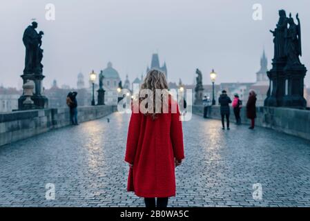 Female tourist walking alone on the Charles Bridge during the early morning in Prague, capital of Czech Republic Stock Photo