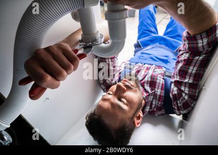 Male Plumber Fixing A Sink In Bathroom Stock Photo