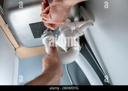 Close-up Of Male Plumber Fixing Sink In Kitchen Stock Photo