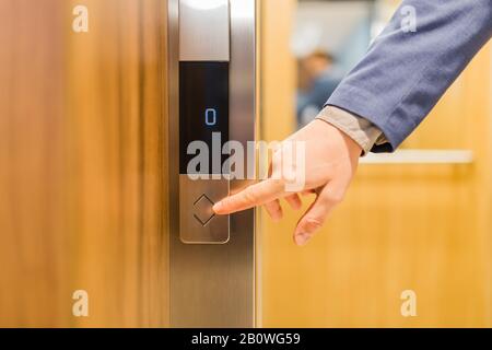 Close up of businessman hand pressing modern elevator button. Space for copy. Stock Photo