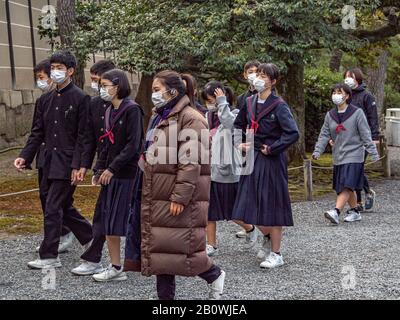 Japanese tourists and schoolchildren wearing protective masks in shadow of coronavirus outbreak. Stock Photo