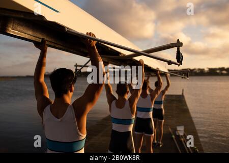 Teammates carrying the rowing boat together Stock Photo