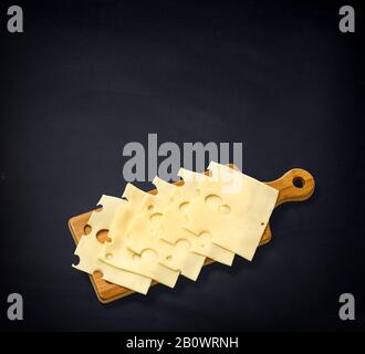cheese slices isolated on board on black background Stock Photo