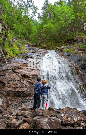 two children at waterfall. Junkerdal National Park,Røkland Stock Photo