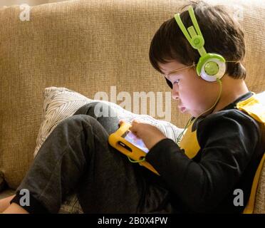 children playing on Amazon Fire tablet listening to headphones Stock Photo