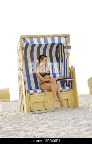 Young woman with laptop on the beach, Niendorf on the Baltic Sea, Schleswig-Holstein, Germany,