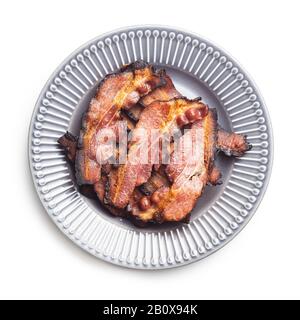 Fried bacon on plate. Sliced roasted bacon isolated on white background. Stock Photo