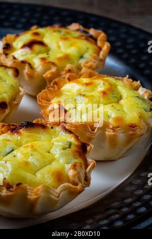 Filo dough pastry cups filled with feta cheese mixture. On a serving plate. Stock Photo