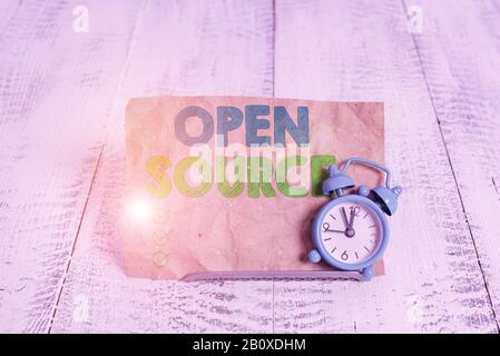 Handwriting text writing Open Source. Conceptual photo denoting software which original source code is made free Mini blue alarm clock stand tilted ab Stock Photo