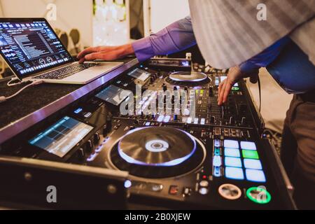 DJ playing at the turntable. Close up with hands on turntable, playing music. Mixing tracks for party at night club. Stock Photo