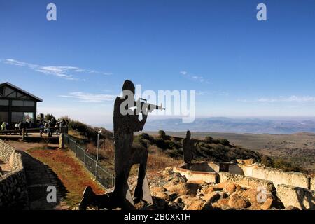 A metal soldier silhouette kneels near the trenches on top of Mount Bental in Israel's Golan Heights, with a view toward Kibbutz Merom Golan. Stock Photo