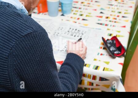 Mature man doing a crossword puzzle and relaxing at home during the day, indoor shot Stock Photo