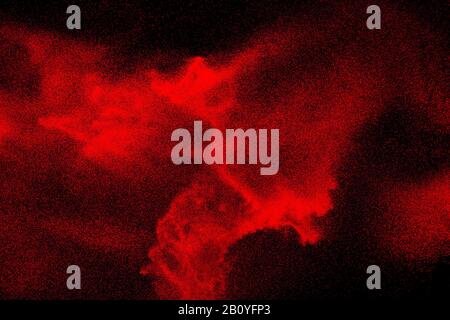 Red dust particles explosioon on black background.Red powder splash. Stock Photo