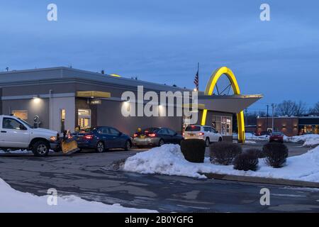 Utica, NY - Feb 12, 2020: Evening View of McDonald's Pickup Window with Cars Line Waiting for Orders. Stock Photo