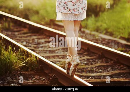 Young woman in dress balancing on a train track, Stock Photo