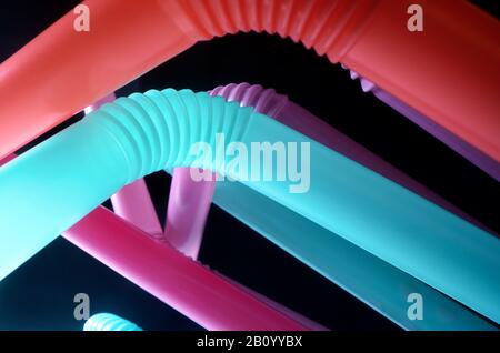 Background from multi-colored plastic cocktail tubes on a dark background Stock Photo