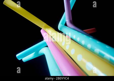 Background from multi-colored plastic cocktail tubes on a dark background Stock Photo