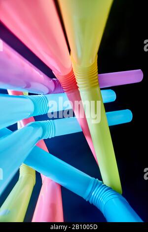Background from multi-colored plastic cocktail tubes on a dark background Stock Photo