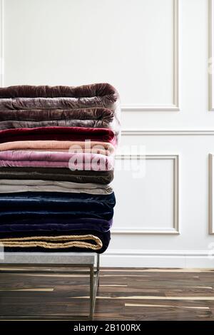 Multi-colored velour bedspreads neatly stacked in a pile in the interior Stock Photo