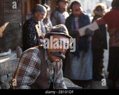 A man wearing a mask takes part during the carnival.Traditional carnival in Sappada, a German speaking town in Dolomiti Mountains in Italy, where people still use their special old-fashioned German dialect, is divided into three Sundays: Sunday of the poor, Sunday of peasants and Sunday of lords. People wear traditional wooden masks named Love and play funny characters to entertain neighbours and visitors. The most important mask is Rollat, huge man in sheep skin coat with wooden face of shepherd. Stock Photo