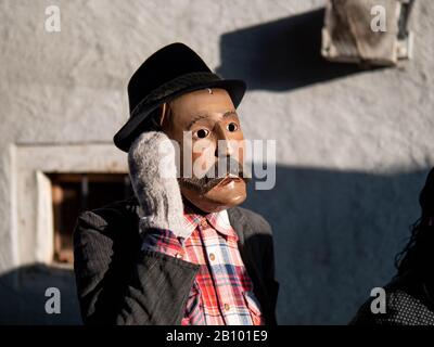 A man wearing a mask takes part during the carnival.Traditional carnival in Sappada, a German speaking town in Dolomiti Mountains in Italy, where people still use their special old-fashioned German dialect, is divided into three Sundays: Sunday of the poor, Sunday of peasants and Sunday of lords. People wear traditional wooden masks named Love and play funny characters to entertain neighbours and visitors. The most important mask is Rollat, huge man in sheep skin coat with wooden face of shepherd. Stock Photo