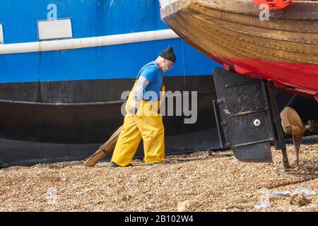 Hastings fisherman helping to haul trawler ashore on the Old Town Stade at Rock-a-Nore, East Sussex, UK Stock Photo