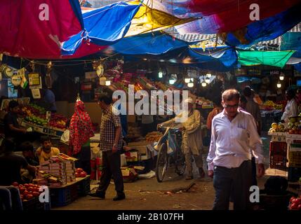 Mumbai, India - December 18, 2019 : Muslim old age man wearing traditional islamic cloths and skull cap walking with bicycle in a fruit market in Sout Stock Photo