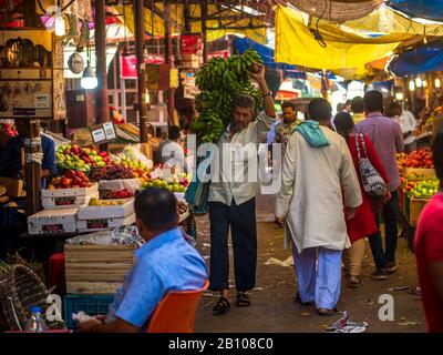 Mumbai, India - December 18, 2019 : A porter carrying bunch of bananas on shoulder in fruit market in South Mumbai Stock Photo