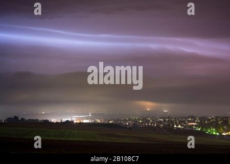 Nocturnal shelf cloud of a thunderstorm illuminated by flashes of light behind Langgöns, Hessen, Germany Stock Photo