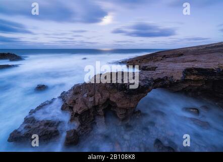 Storm on the stony coast with surf in the moonlight at dawn, Cabo Raso, Estoril, Lisbon, Portugal Stock Photo
