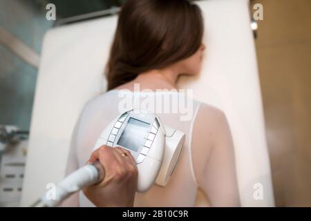Young beautiful woman and LPG massage back procedure in spa clinic. Lymphatic drainage massage LPG apparatus process. Stock Photo