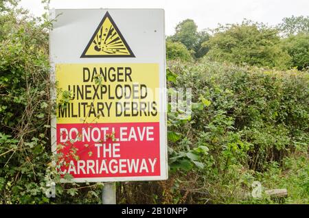 Sign beside a road on Salisbury Plain warning of unexploded ordnance.  The area is usually closed to visitors and is used by the British Army for trai Stock Photo