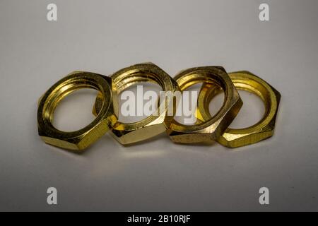 High detail close-up macro of four arranged gold screw nuts isolated on white background in partial focus Stock Photo