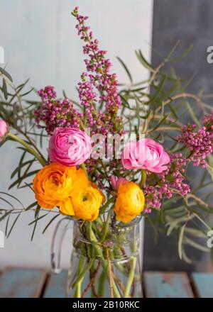 Closeup view of a bouquet of colorful ranunculus flowers, some eucalyptus branches and some wild pink flowers. Stock Photo