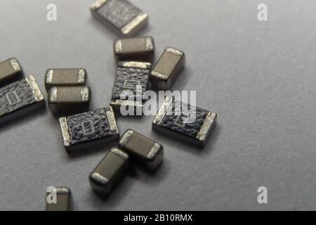 Abstract close-up of grey scattered 0603 SMT surface mount chip MLCC capacitors and 1206 resistors power electronics components on white background in Stock Photo