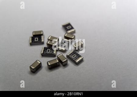 Abstract close-up of grey scattered 0603 SMT surface mount chip MLCC capacitors and 1206 resistors power electronics components on white background in Stock Photo