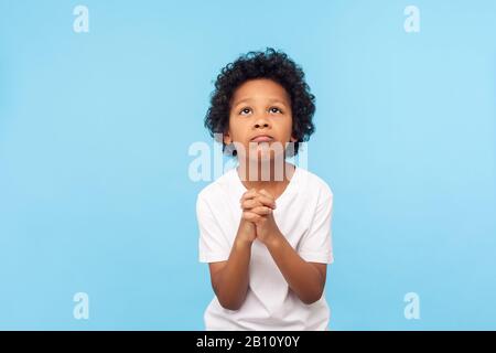 Please, I'm begging. Portrait of upset little boy praying to god with hands held together, apologizing for bad behavior, looking up with imploring eye Stock Photo