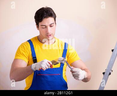 The young contractor employee applying plaster on wall Stock Photo