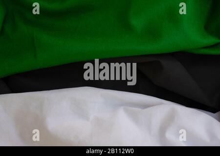 Cloth waves close up the background, Stacked Creased fabric 3 color black green white, elegant wallpaper design, wavy folds of grunge silk texture sat Stock Photo