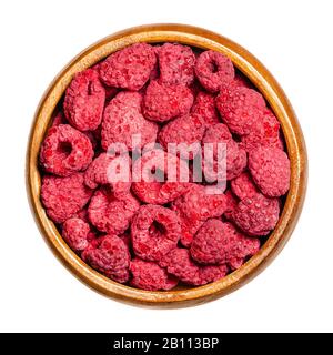Dried whole raspberries in a wooden bowl. Edible, ripe, red and sweet fruits of Rubus idaeus, the cultivated European raspberry. Closeup, from above. Stock Photo