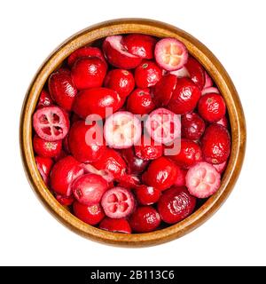 Sliced and dried cranberries in a wooden bowl. Edible and ripe fruits of Vaccinium macrocarpon, red berries with an acidic taste. Closeup, from above. Stock Photo