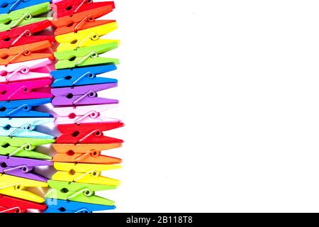 Many multi colored wooden decorative clothespins lies in row. Multicolor background. Copy space. Isolated on white. Close-up. Stock Photo