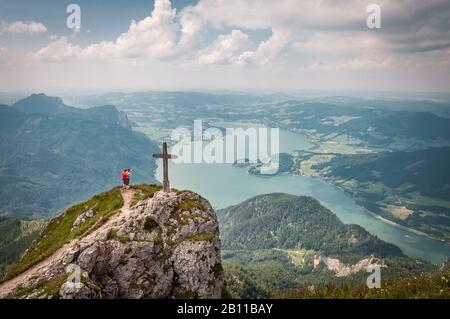 two people standing on the pinnacle of the Austrian mountain Schafberg with the lake Mondsee in the background Stock Photo