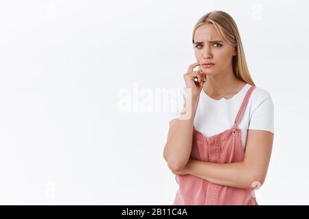 Girl feeling concern and doubts, thinking about something troublesome and upsetting, frowning suspicious stare skeptical with disbelief touch face Stock Photo