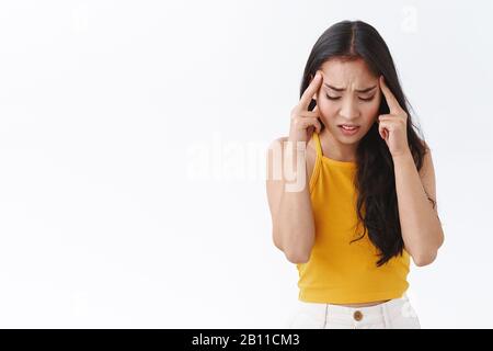 Troubled east-asian woman panic and worry, trying remember something or think as feeling nervous, distressed, girl pressured during deadline, touching Stock Photo