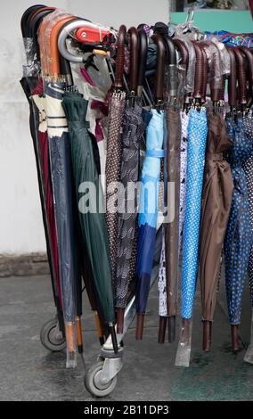 Many different curve handle umbrellas displayed for sale on a street on a rainy day Stock Photo