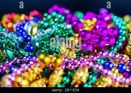 A colorful group of plastic festival beads with a dark bluish background.  Selective focus.  Blurred foreground.  Blurred background. Stock Photo