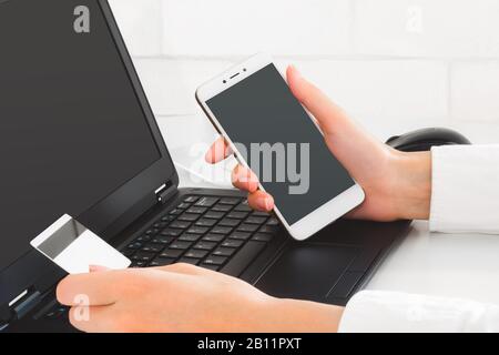 Online payment by using laptop and mobile phone. Hands holding credit card and mobile device to make online transaction. Business mockup Stock Photo