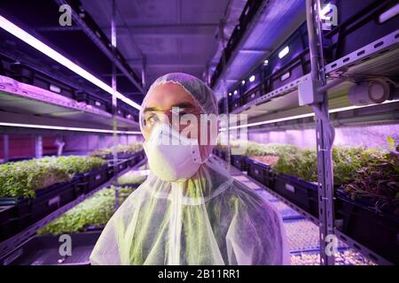 Portrait of young man in protective workwear looking at camera while standing in greenhouse Stock Photo