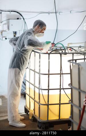 Young man in protective clothing working with a water pump in the factory Stock Photo